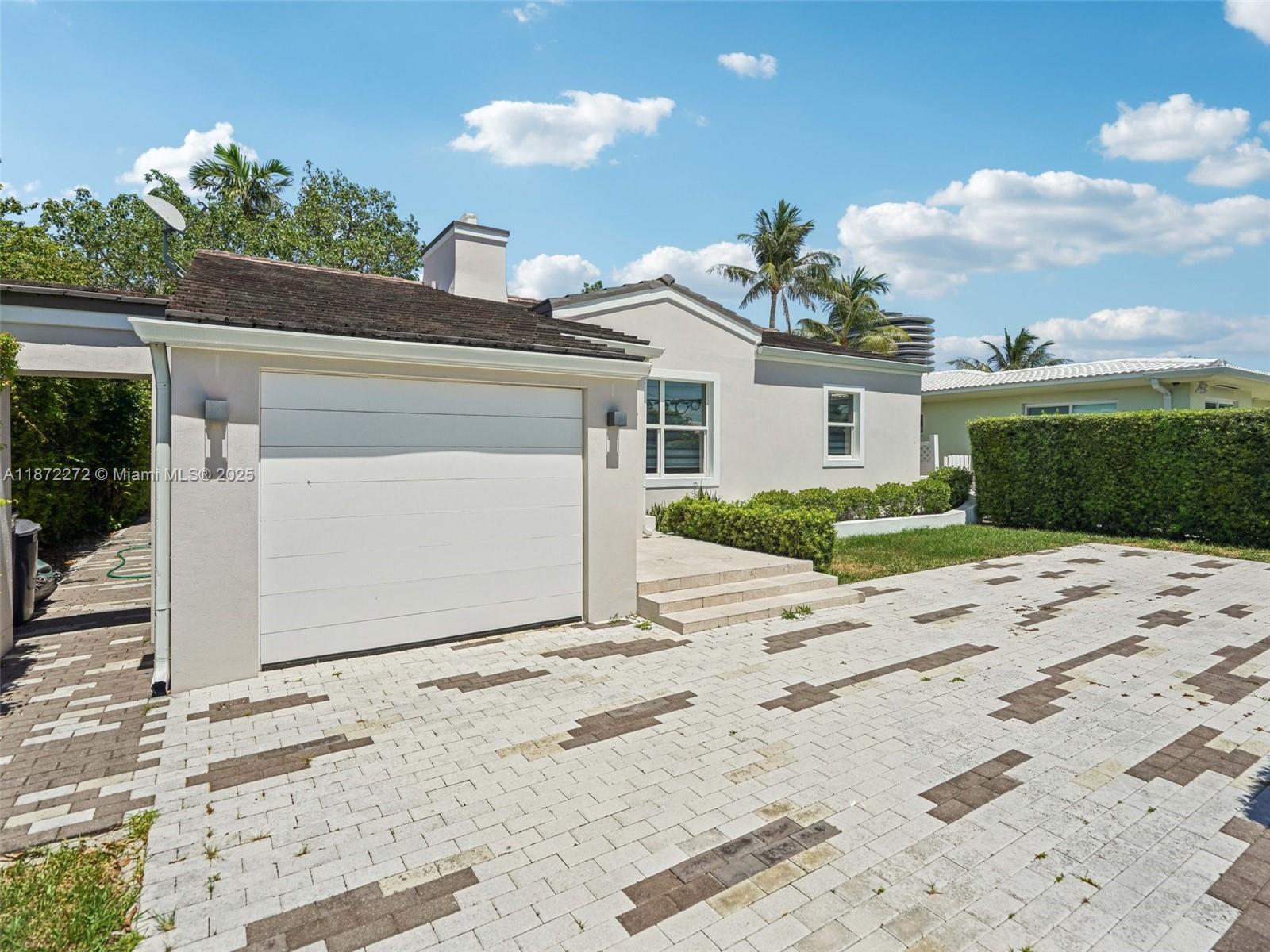 8875 Abbott Avenue Surfside, FL 33154 - Photo 4 of 45 a front view of a house with a yard and garage