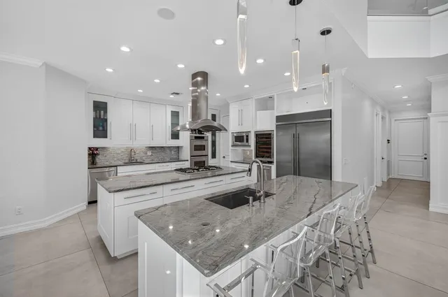 a kitchen with stainless steel appliances kitchen island granite countertop a stove a sink dishwasher and white cabinets with wooden floor