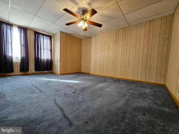 an empty room with windows and a chandelier fan