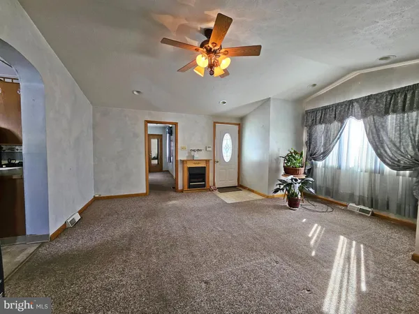 a view of an empty room with a fireplace and a chandelier fan