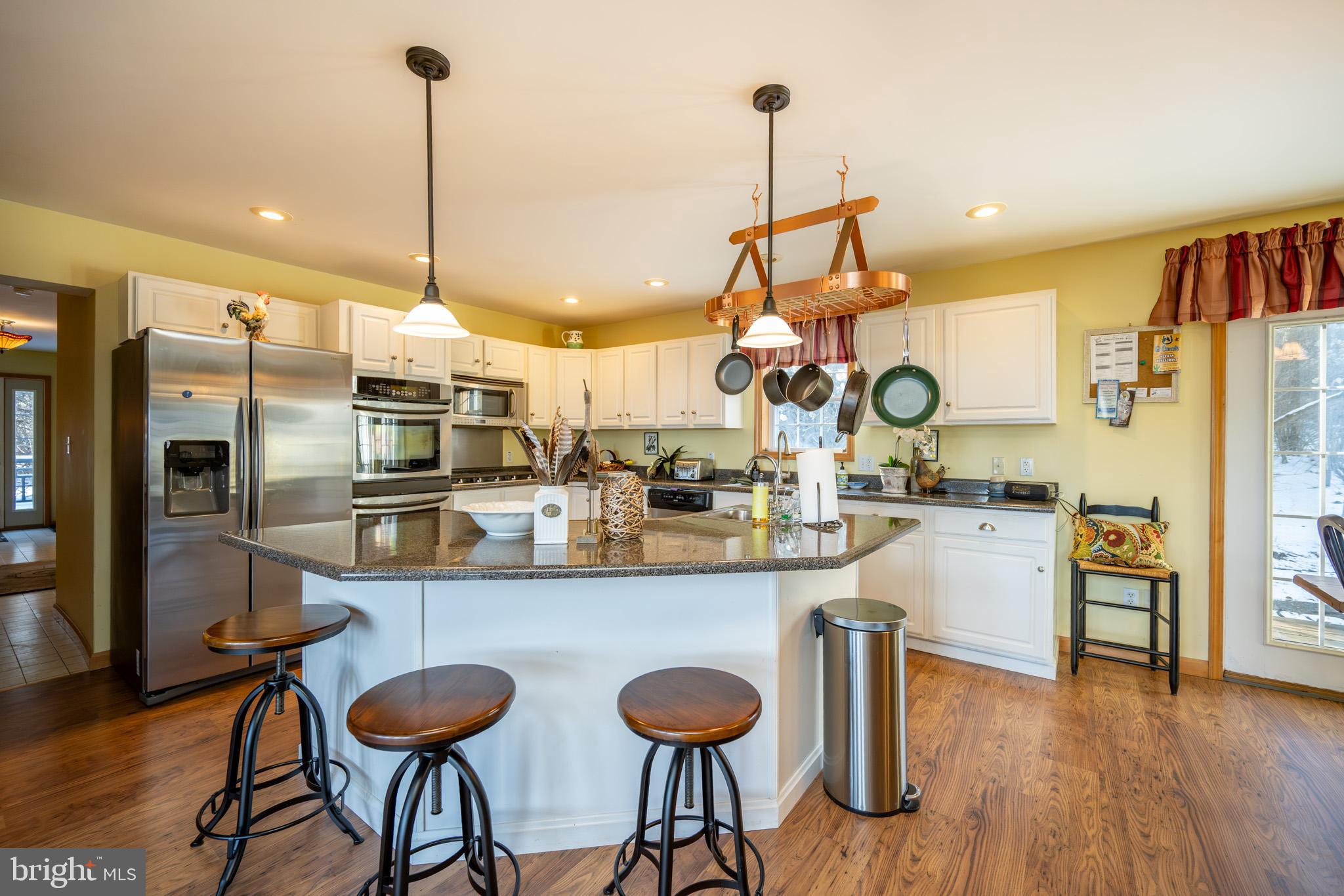 3836 Chestnut Grove Road Swanton, MD 21561 - Photo 57 of 111 a kitchen with stainless steel appliances kitchen island granite countertop a table chairs in it and wooden floors