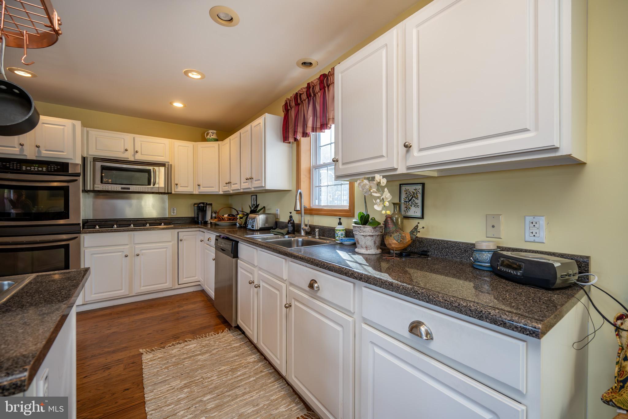 3836 Chestnut Grove Road Swanton, MD 21561 - Photo 58 of 111 a kitchen with kitchen island granite countertop white cabinets and white appliances