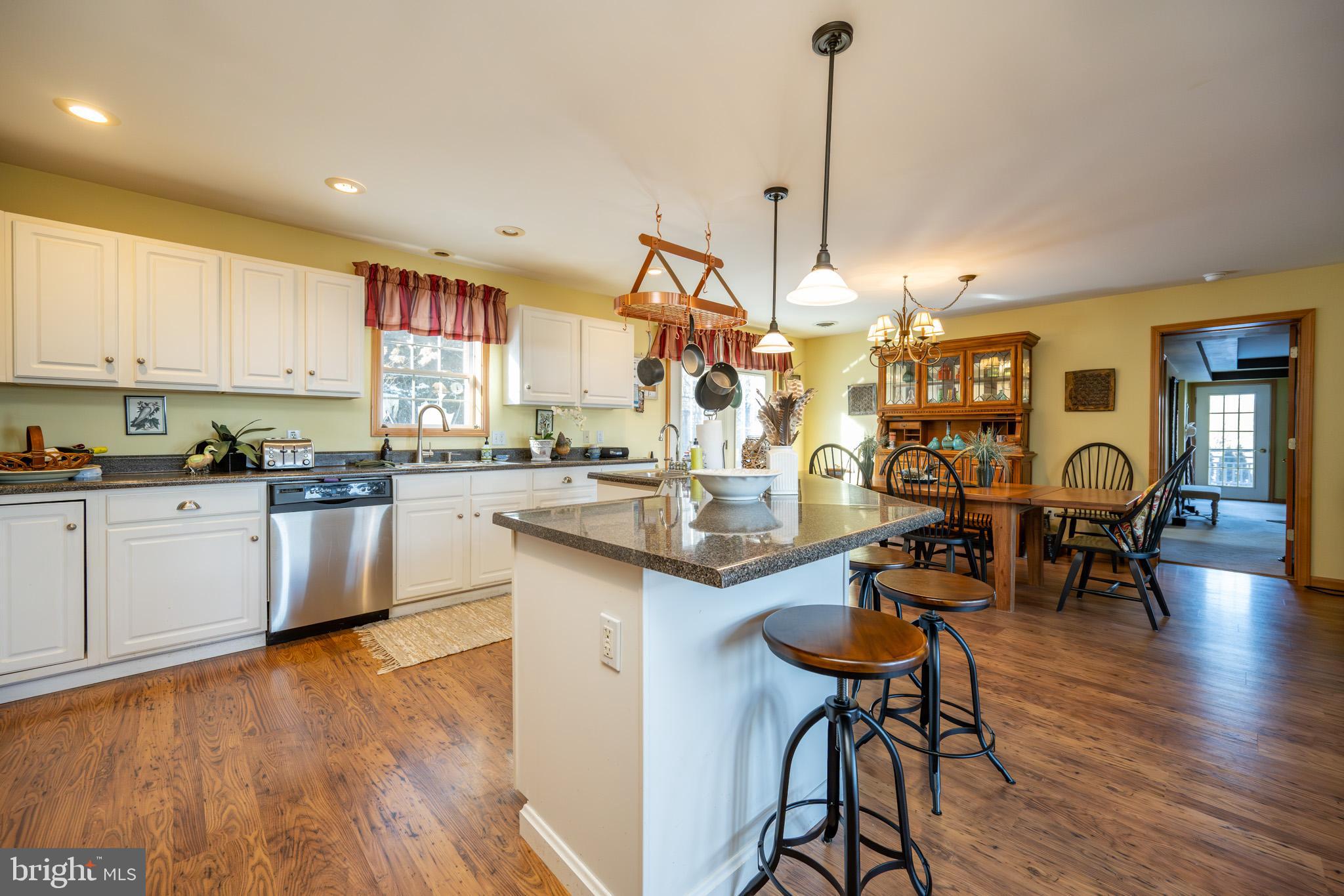 3836 Chestnut Grove Road Swanton, MD 21561 - Photo 63 of 111 a kitchen with stainless steel appliances kitchen island granite countertop a table chairs stove and white cabinets