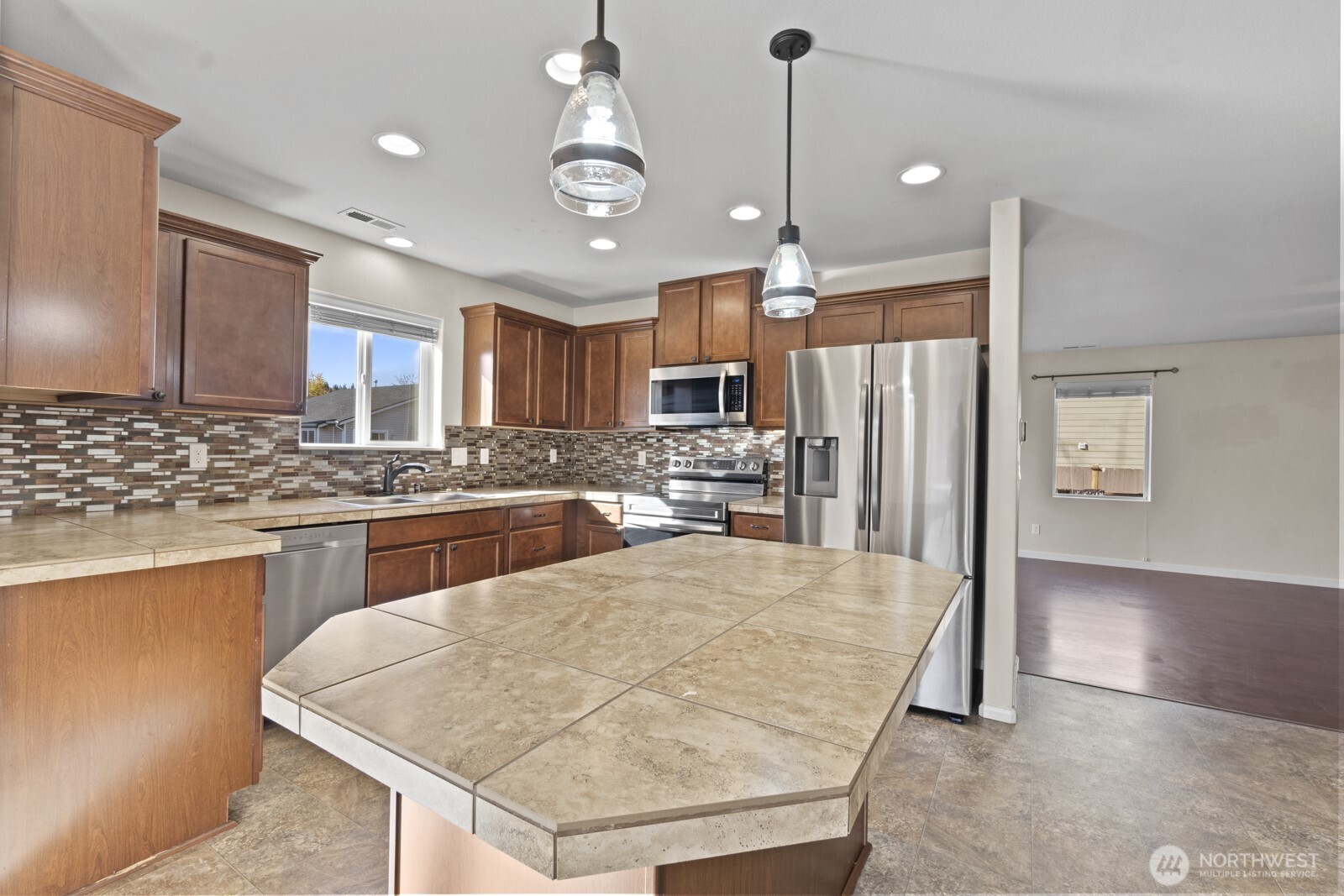 1105 Sigafoos Avenue Northwest Orting, WA 98360 - Photo 11 of 40 a kitchen with stainless steel appliances kitchen island granite countertop a refrigerator a stove top oven and a sink with cabinets