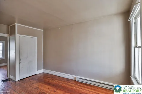 a view of an empty room with wooden floor and a window