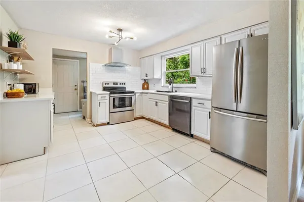 a kitchen with granite countertop a refrigerator and a stove top oven