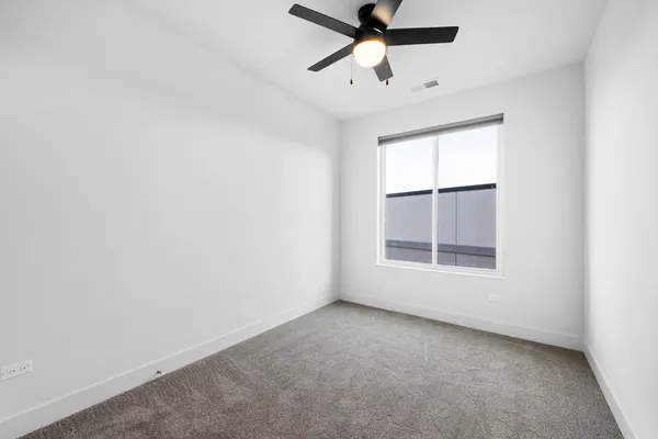 an empty room with a window and a fan