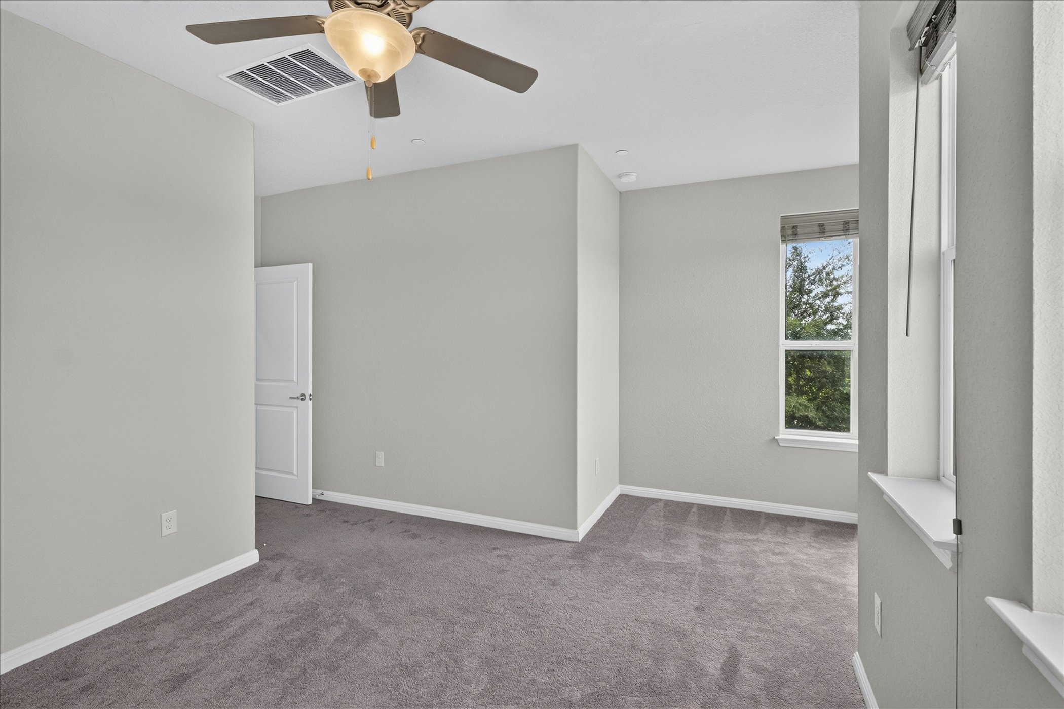 9015 Cattle Baron Path, Unit 1102 Austin, TX 78747 - Photo 15 of 25 A well-lit bedroom features plush carpeting and a modern ceiling fan, offering comfort and style.