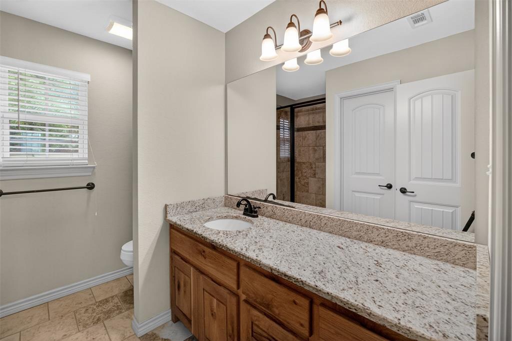 505 East 5th Street Springtown, TX 76082 - Photo 18 of 39 a bathroom with a granite countertop double vanity sink a mirror and a shower