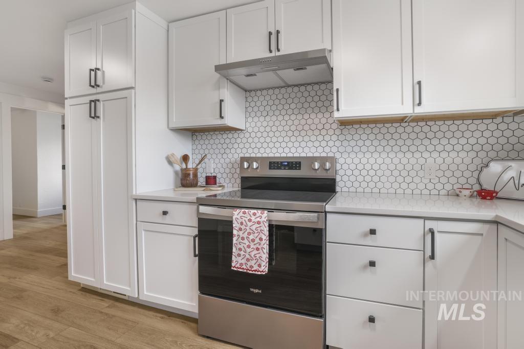344 Fillmore Street Twin Falls, ID 83301 - Photo 13 of 42 Kitchen with electric range, white cabinets, decorative backsplash, under cabinet range hood, and light stone countertops