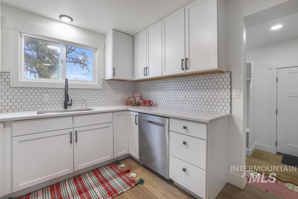 344 Fillmore Street Twin Falls, ID 83301 - Photo 14 of 42 Kitchen with white cabinetry, stainless steel dishwasher, light stone countertops, light wood-style flooring, and decorative backsplash