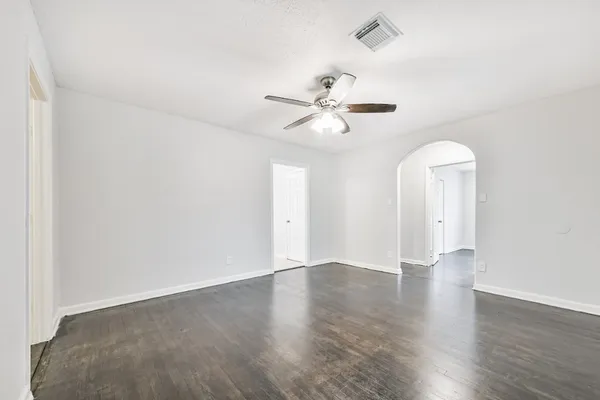 an empty room with wooden floor ceiling fan and window