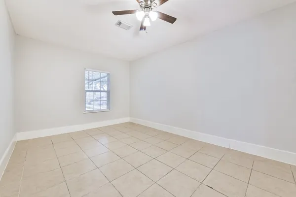 an empty room with windows and fan