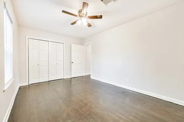 an empty room with a ceiling fan and wooden floor