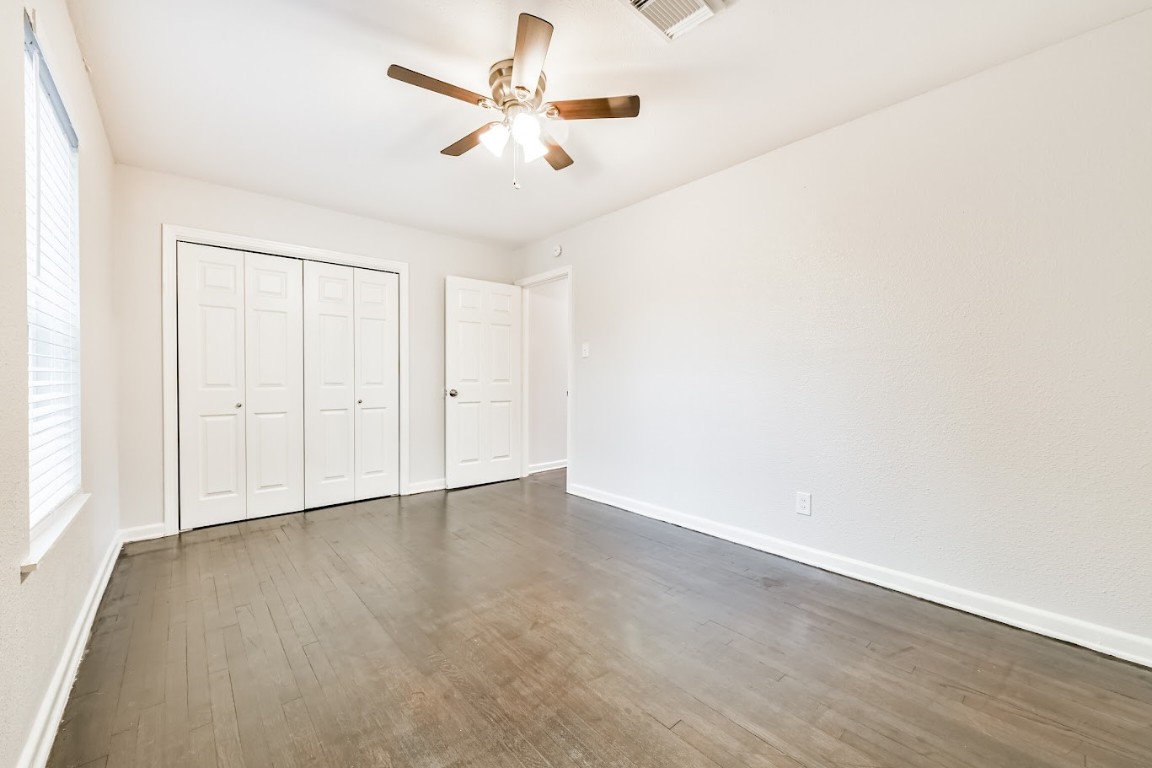 5855 Beldart Street Houston, TX 77033 - Photo 19 of 26 an empty room with a ceiling fan and wooden floor