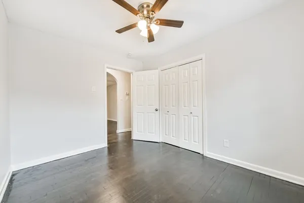 an empty room with a ceiling fan and wooden floor