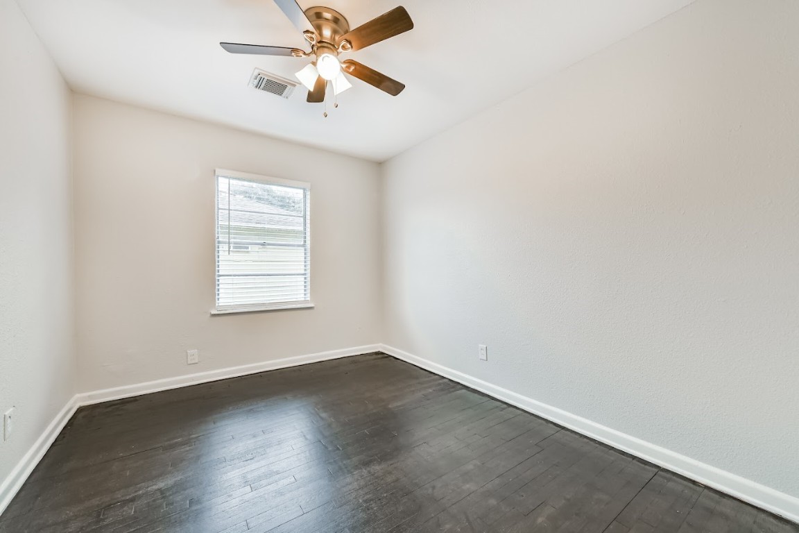 5855 Beldart Street Houston, TX 77033 - Photo 22 of 26 an empty room with wooden floor ceiling fan and windows