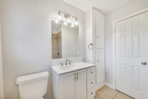 a bathroom with a toilet a sink a mirror and vanity