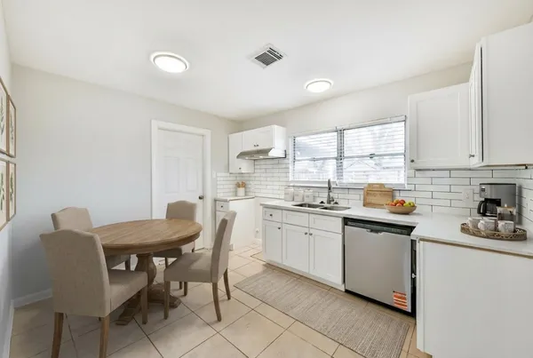 a kitchen with stainless steel appliances granite countertop a sink a stove a dining table and chairs