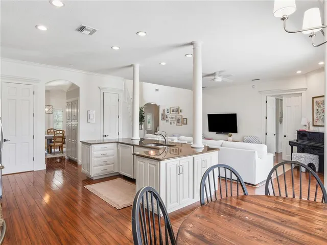 a kitchen with stainless steel appliances kitchen island granite countertop a stove top oven a sink a dining table and chairs with wooden floor