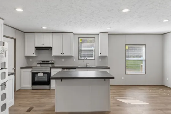 a kitchen with granite countertop kitchen island stainless steel appliances a sink stove and refrigerator