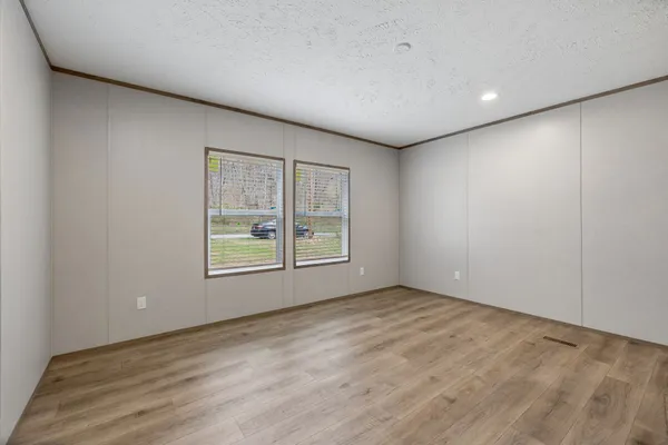 a view of an empty room with wooden floor and closet