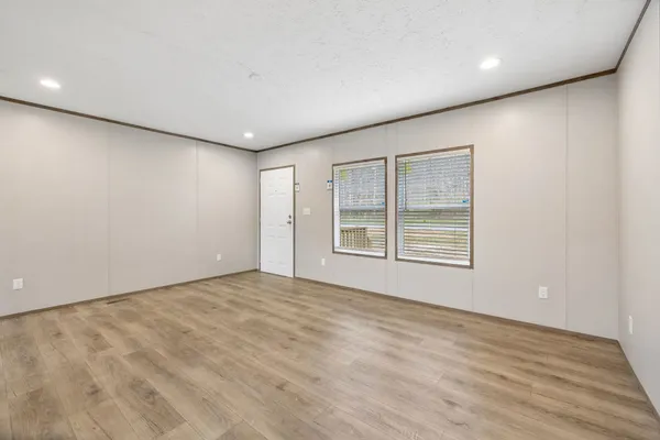 an empty room with wooden floor and windows
