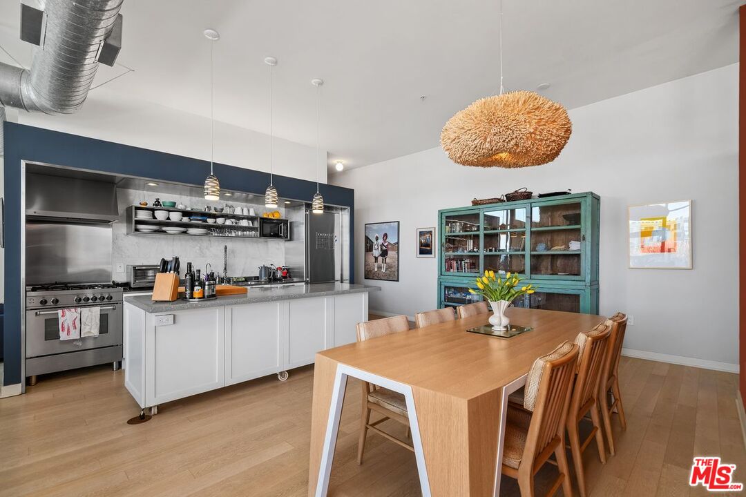 4080 Glencoe Avenue, Unit 420 Marina del Rey, CA 90292 - Photo 6 of 40 a kitchen with stainless steel appliances granite countertop a stove a refrigerator a sink a dining table and chairs with wooden floor