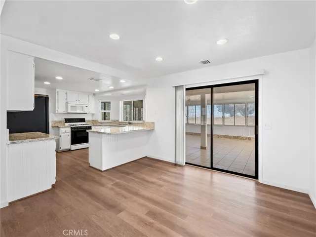 a large white kitchen with a refrigerator a stove top oven a sink and dishwasher with wooden floor