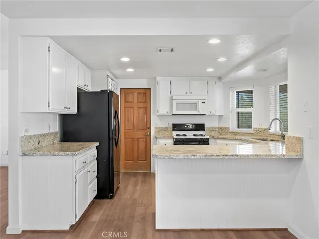 a kitchen with a refrigerator a stove top oven a sink and cabinets