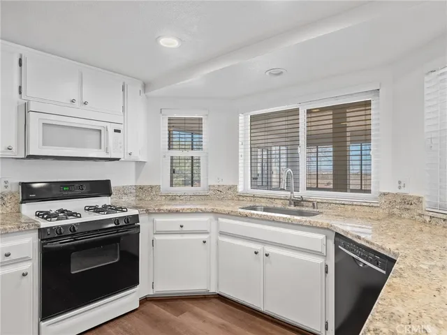 a kitchen with stainless steel appliances granite countertop white cabinets and a sink