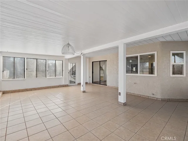 a view of an empty room with chandelier fan