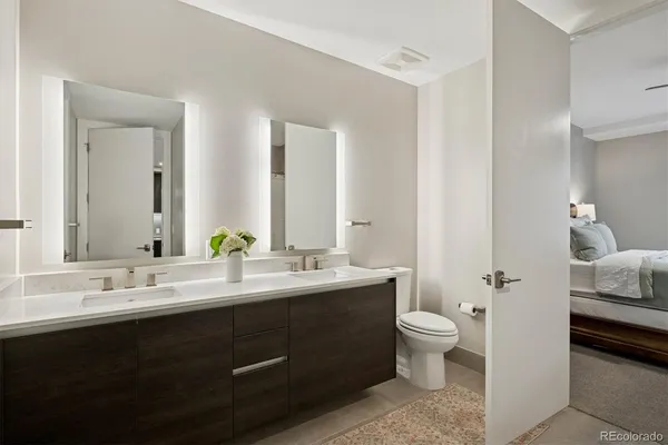 a en suite bathroom with a double vanity sink toilet mirror and a tub