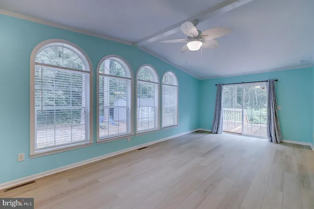 an empty room with windows and fan