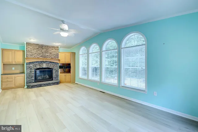 an empty room with a fan & a window