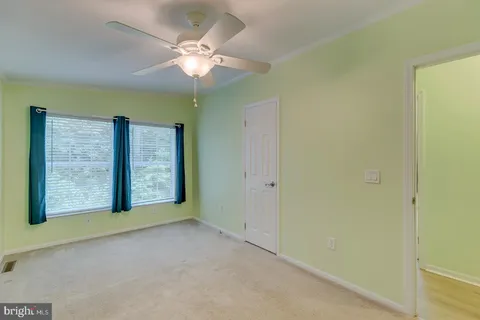 an empty room with a chandelier fan and closet area