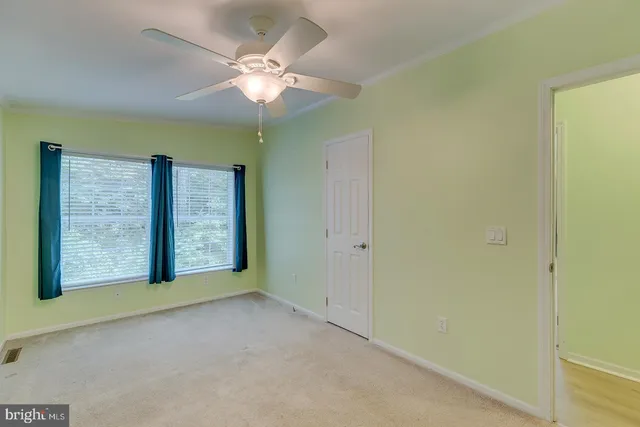 an empty room with a chandelier fan and closet area