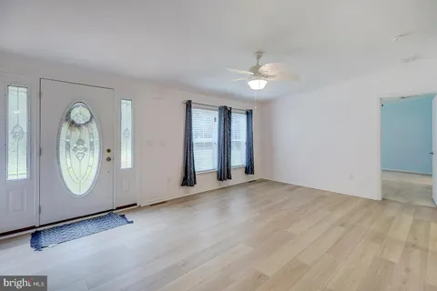 a view of an empty room with wooden floor and a ceiling fan