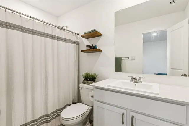 a bathroom with a sink a toilet and shower curtain