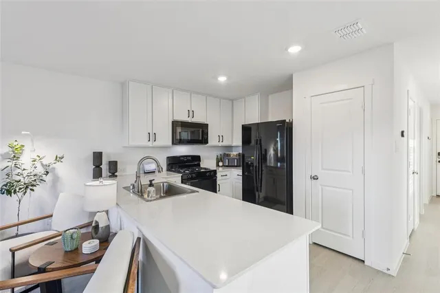 a kitchen with granite countertop a refrigerator a sink a stove a dining table and chairs