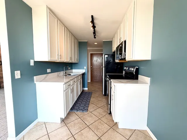 a kitchen with a sink a stove top oven a washer dryer and white cabinets
