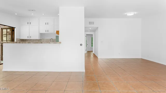 a view of kitchen with refrigerator and white cabinets
