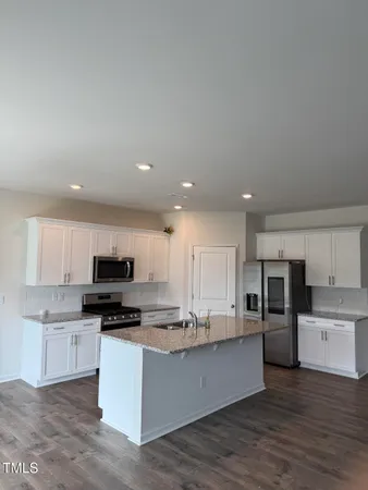 a kitchen with stainless steel appliances granite countertop a stove top oven a sink and white cabinets