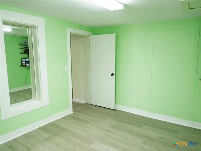 a view of an empty room with closet and wooden floor