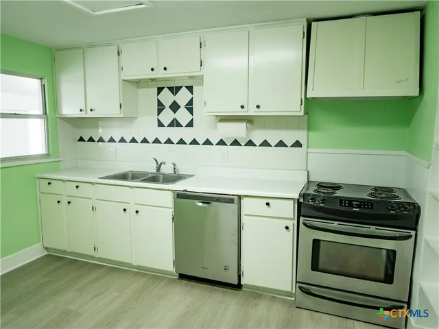 a kitchen with granite countertop white cabinets and stainless steel appliances