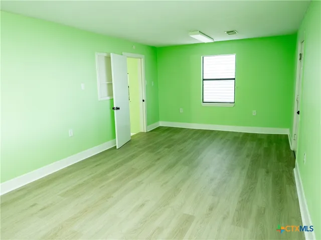 a view of an empty room with window and a kitchen