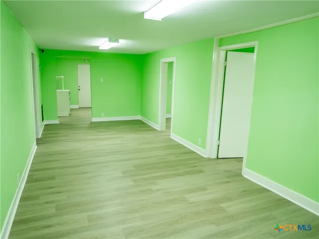a view of an empty room with kitchen and window