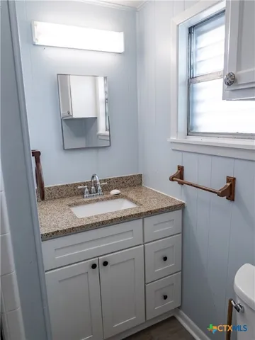 a bathroom with a granite countertop sink and a mirror
