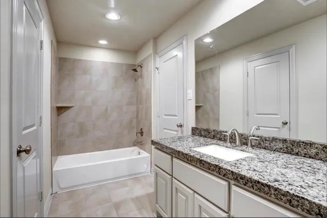 a bathroom with a granite countertop double vanity sink and mirror with bathtub