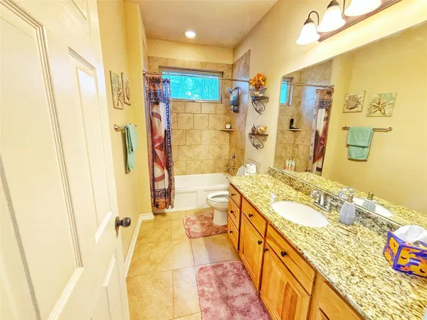 a spacious bathroom with a granite countertop double vanity sink a mirror a bathtub and shower